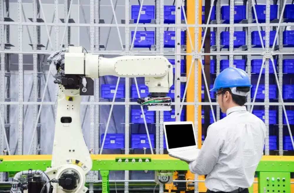 Man using a laptop looking at a robotic controls machine