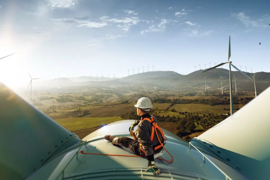 Energy employee sitting on wind turbine looking at sunset