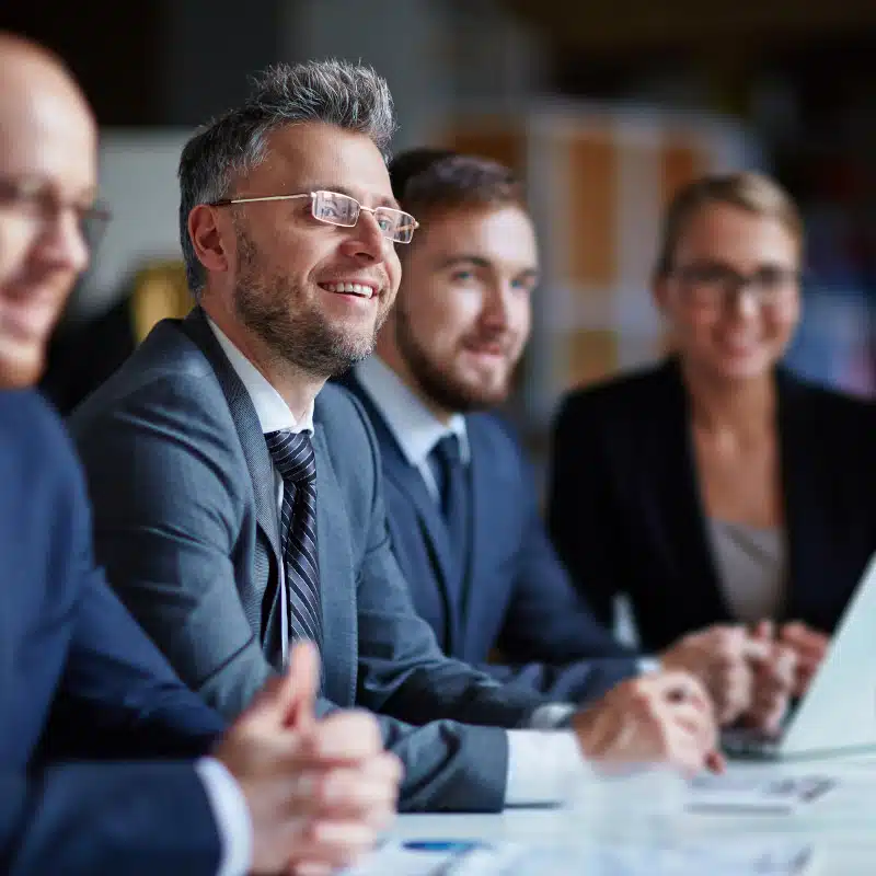 Executive professional smiling with team around him