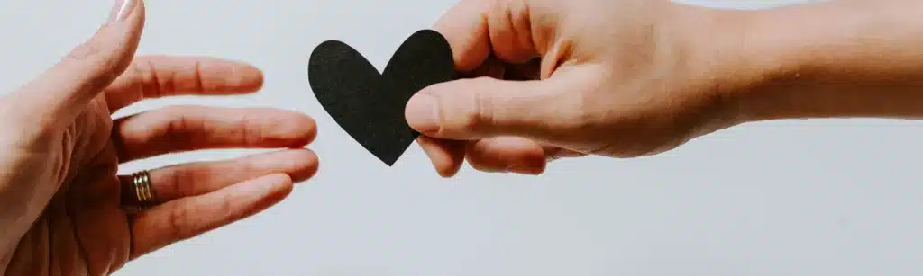 Image of two hands holding a black heart