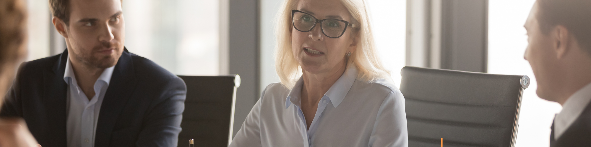 Female executive with two senior male colleagues in boardroom