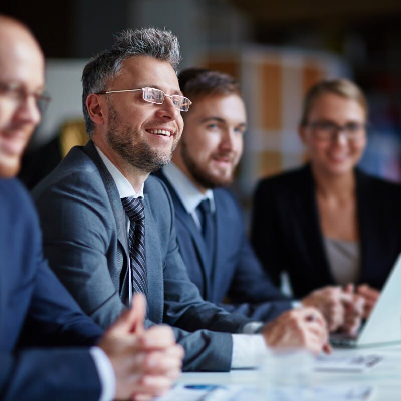 Search & Selection 1 800x800 Executive professional smiling with team around him